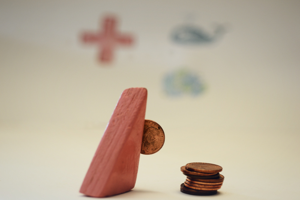 Block Woman holds one penny with a stack of pennies on the floor next to her. She is looking at some symbols of charities on the wall.