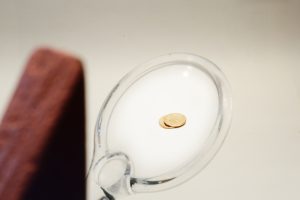 Block Women examining 2 pennies through a magnifying glass