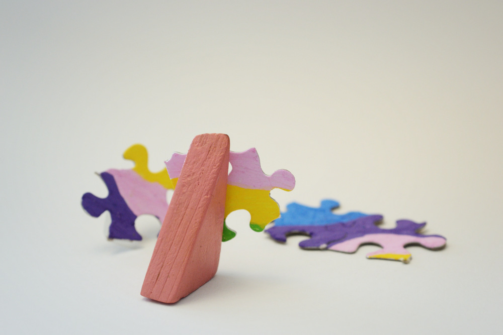 Block Woman looks at a jumbled pile of multi-colored puzzle pieces.