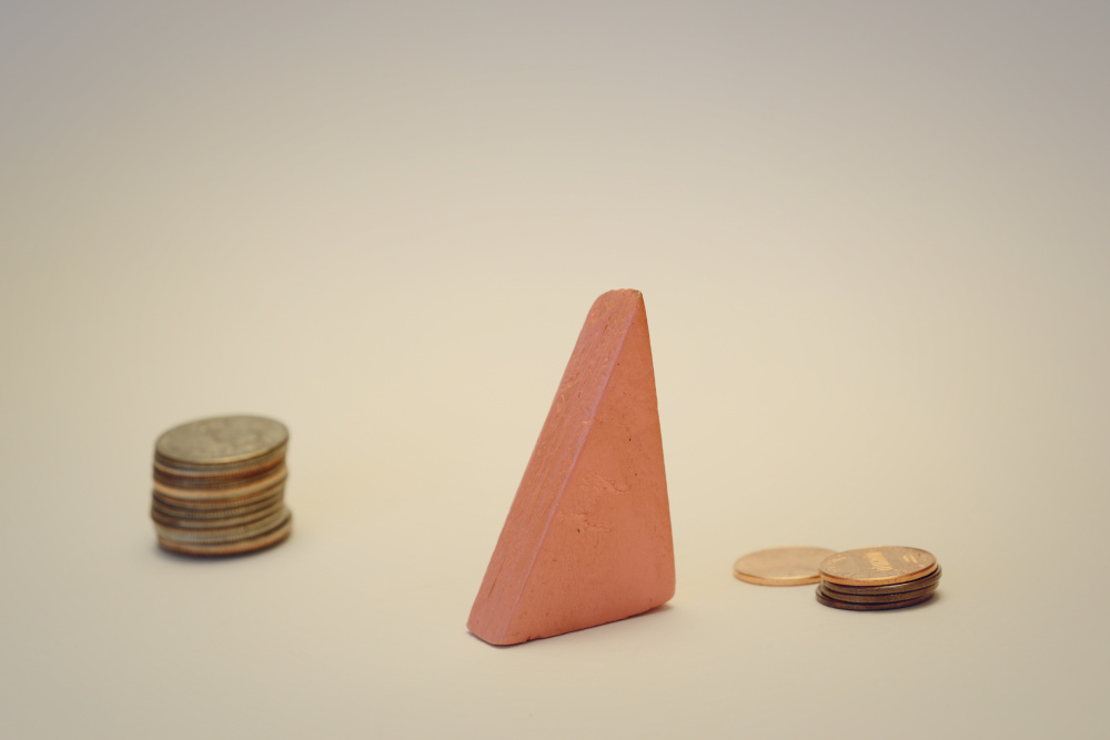 Block Woman is standing between two piles of coins, one higher and one smaller