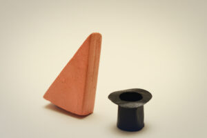 Block Woman, a pinkish triangle block on the left, is tipping slightly towards an upturned black top hat.