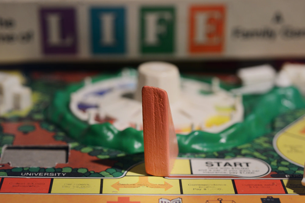 Block Woman stands at the start of a blurry game board of Life.