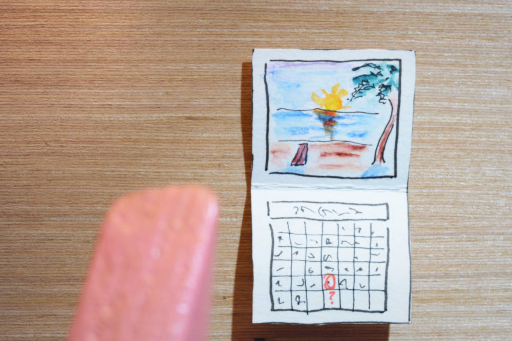 Block Woman gazes at a wall calendar with a beach scene and a date circled on the calendar page.