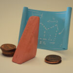 Block Woman, with a pile of pennies on either side, looks at a blueprint paper with white outlines of a house.